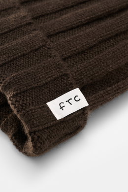 Close-up, angled view of the FTC Cashmere beanie dark brown showing its rib knit brioche pattern, medium-fine knit, and variable brim with FTC woven label, made from pure, very soft Fair Trade cashmere, a luxurious winter accessory no wardrobe should be w