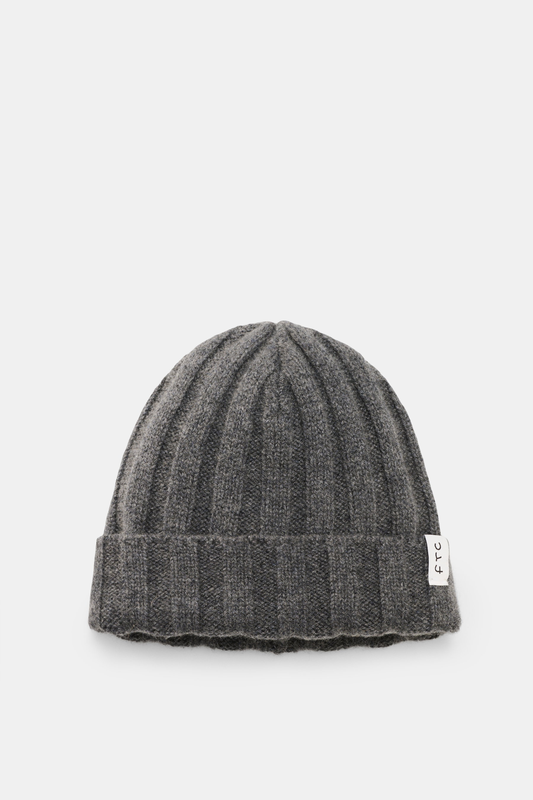 Nahaufnahme der FTC Cashmere Mütze dunkelgrau von oben, Rippstrick, mittelfeines Strickbild, schmaler Umschlag mit FTC-Label, reiner Cashmere, sehr weicher Griff, luxuriöses Winteraccessoire.