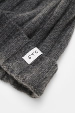 Close-up top-side view of the FTC Cashmere Beanie dark grey showing ribbed knit pattern, narrow cuff with FTC woven label, pure cashmere, very soft feel, and medium-fine knit texture, a luxurious winter accessory.