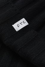 Close-up front perspective of the FTC Cashmere beanie black showing the white FTC woven label on its rib knit, medium-fine brioche pattern, and pure cashmere texture.

Description:
<p>Luxurious winter accessory: This rib knit beanie in the finest Fair Tra