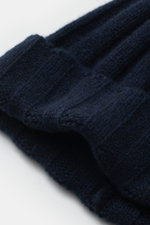 Nahaufnahme der FTC Cashmere Mütze navy aus feinstem Fair-Trade Cashmere mit Rippstrickmuster, schmalem Umschlag und FTC-Weblabel.