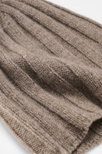 Close-up angled view of the FTC Cashmere Beanie Taupe showing its ribbed knit pattern, medium-fine texture, and narrow cuff with FTC label. Luxurious winter accessory: This ribbed knit beanie is made from finest fair-trade cashmere and is a classic that s