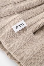 Close-up top view of the FTC Cashmere beanie sand showing its rib knit texture, medium-fine brioche pattern, and white woven FTC label on the variable brim, made from pure Fair Trade cashmere with a very soft feel.