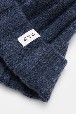 Close-up view of the FTC Cashmere Beanie grey blue, showing the ribbed knit pattern, medium-fine knit texture, narrow cuff, and white FTC woven label; luxurious winter accessory made from pure fair-trade cashmere with a very soft feel.