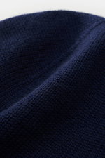 Nahaufnahme der Polo Ralph Lauren Wollmütze navy aus reiner Wolle, weicher Griff, feiner glatter Strick, breiter Rippstrick-Umschlag, Polospieler-Stitching.