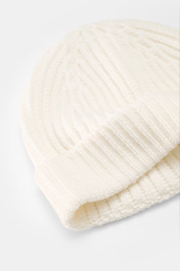 Close-up top-down view of 04651/ A trip in a bag Wool Hat 'Foggy' offwhite showing pure virgin wool, patent knit, soft touch, medium coarse knit pattern, and narrow cuff.