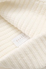 Close-up image taken from a slightly angled top view of the 04651/ A trip in a bag Wool Hat 'Foggy' offwhite, showcasing pure virgin wool, patent knit, soft touch, medium coarse knit pattern, and narrow cuff.