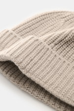 Nahaufnahme der 04651/ A trip in a bag Cashmere Mütze taupe mit breitem Umschlag, mittelfeinem Strickbild und markantem Patentstrickmuster aus weichem, reinem Cashmere, fotografiert aus schräger Perspektive.