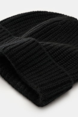 Nahaufnahme der 04651/ A trip in a bag Cashmere Mütze schwarz mit breitem Umschlag und markantem Patentstrickmuster, mittelfeines Strickbild, sehr weicher Griff aus reinem Cashmere, fotografiert aus schräger Perspektive.