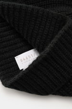 Nahaufnahme der 04651/ A trip in a bag Cashmere Mütze schwarz mit breitem Umschlag und markantem Patentstrickmuster, fotografiert aus schräger Perspektive. Luxuriöser Cashmere für kalte Tage: Die Mütze von 04651/ A TRIP IN A BAG präsentiert sich mit ihrem