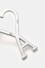 A close-up, top-down view of the Ami Paris Schlüsselanhänger silber, a silver unisex keychain shaped as an 'A' with a heart-shaped carabiner featuring the AMI logo and engraved "ami". <p>Unisex Accessoire von AMI PARIS: Dieser praktische Begleiter mit dem