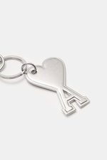 Close-up of Ami Paris Schlüsselanhänger silber keychain with heart-shaped 'A' logo charm and practical carabiner, photographed from above.

Description: <p>Unisex Accessoire von AMI PARIS: Dieser praktische Begleiter mit dem markentypischen 'A' mit Herz h