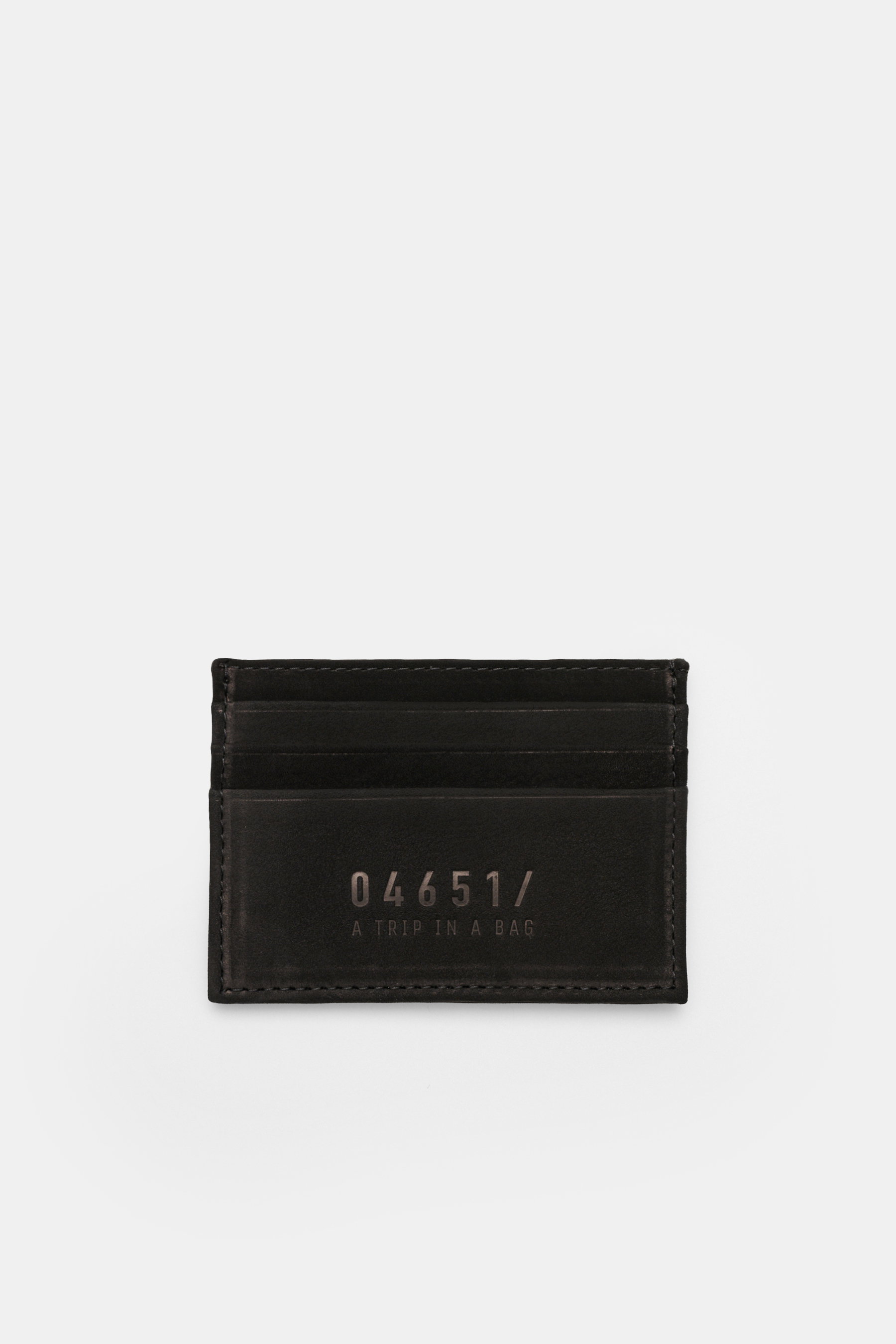 Top-down view of the 04651/ A trip in a bag Credit card holder black in premium suede, showing six card pockets and 04651/ embossing.

Description:  
<p>A minimalist everyday essential: This flat credit card holder in premium suede by 04651/ A TRIP IN A B