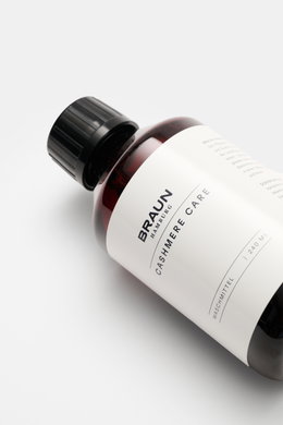 BRAUN Hamburg Waschmittel 'Cashmere Care' 100 ml bottle photographed from a top-side angle on a white surface, with a peach-scented formula for wool and cashmere care. Hochwertige Pflege für Ihre Cashmere- und Wollprodukte: Das 'Cashmere Care' Waschmittel