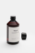 BRAUN Hamburg Waschmittel 'Cashmere Care' 100 ml bottle photographed from a slightly elevated front angle, with the black cap removed and placed beside it. Hochwertige Pflege für Ihre Cashmere- und Wollprodukte: Das 'Cashmere Care' Waschmittel mit dezente