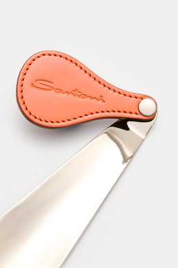 Santoni Schuhlöffel silber mit flexiblem, orangefarbenem Ledergriff und SANTONI-Prägung, seitliche Nahaufnahme, Maße ca. 14x4,5x1,5 cm.