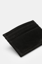 04651/ A trip in a bag Kartenetui schwarz aus edlem Veloursleder, flach, mit sechs Kartensteckfächern, geprägtem Logo, ca. 10x8 cm, Detailaufnahme von schräg oben.