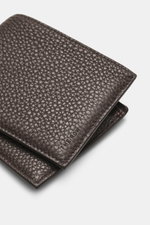 The Row Portemonnaie 'Classic Wallet' dunkelbraun aus fein genarbtem Leder, geprägtem Logo, sechs Kartenfächern, Banknotenfach, Nahaufnahme von oben.