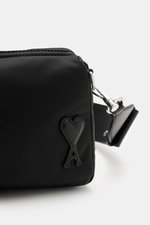Ami Paris Schultertasche 'Marcel' schwarz, Frontdetail Herz-A, glänzende Microfaser, glatter Griff, Reißverschluss, seitliche Nahaufnahme.