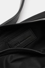 Nahaufnahme der offenen Ami Paris Schultertasche 'Marcel' schwarz, glänzende Microfaser mit Leder-Details und Reißverschluss, Innenfach sichtbar.