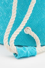 Nahaufnahme des türkisfarbenen 04651/ A trip in a bag Frottee-Seesack 'Terry Sac' mit ornamentaler Struktur und weißem Kordelband, seitliche Perspektive.