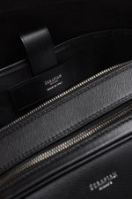 Close-up interior view of the Serapian Briefcase black in robust 'Evoluzione' grained calfskin, showing zippered compartments, embossed logo, and fine textile lining.