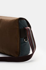 Side view of Barbour Umhängetasche 'Tarras' braun/petrol in waxed cotton with leather details, silver hardware, and striped shoulder strap.