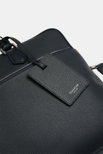 Serapian Aktentasche dark navy aus markant genarbtem Kalbleder mit silberfarbener Hardware, abnehmbarem Schultergurt, Außenfach, Logo und Trolleylasche, frontal nah.