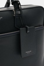 Serapian Aktentasche dark navy aus markant genarbtem Kalbleder, silberner Hardware, abnehmbarem Gurt, frontal nah fotografiert.