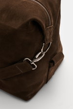 Nahaufnahme des dunkelbraunen 04651/ A trip in a bag Weekender '3-Day-Bag' aus edlem Veloursleder mit silberfarbener Hardware, verstellbarem Schulterriemen und robusten Griffen, seitliche Perspektive zeigt den abnehmbaren Schultergurt und das Reisepass-Au
