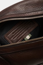 Close-up inside view of the Officine Creative Toiletries bag dark brown showing fine grained calfskin, silver zipper, and interior label, photographed from above.