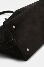 Nahaufnahme des Bodens und Seitenbereichs des 04651/ A trip in a bag Weekender '3-Day Bag' schwarz aus Veloursleder, mit anthrazitfarbener Hardware, weichem Griff und verstellbarem Schultergurt, fotografiert von schräg oben.