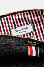 Nahaufnahme der geöffneten Thom Browne Dokumentenmappe schwarz aus fein genarbtem Leder, goldfarbene Hardware, Innenfutter mit rot-blau-weißem Streifendesign, Blick von oben ins geräumige Hauptfach.