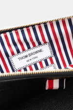 Nahaufnahme des Innenfutters der Thom Browne Dokumentenmappe schwarz mit Streifendesign und THOM BROWNE Label, goldfarbener Reißverschluss.