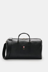 Front view of the Thom Browne Weekender schwarz in black grained leather with gold hardware, sturdy handles, and adjustable shoulder strap.  
<p>Bereit für den nächsten Kurztrip: Der geräumige Weekender von THOM BROWNE aus edlem, fein genarbtem Leder vere