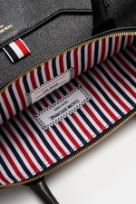 Close-up top view of the interior and textured leather exterior of the Thom Browne Shopper schwarz, showing gold zipper and striped textile lining.

Additional description: <p>Souveräner Stil für jeden Tag: Der geräumige Shopper von THOM BROWNE aus fein g