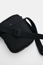Stone Island Crossbody Bag 'Marsupio Tracolla' black shown from a top-front angle, made of high-quality microfiber, with a robust adjustable strap, outer zip pocket, snap button outer and inner pockets, and the signature patch, approx. 16x19x5 cm, practic