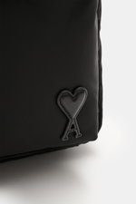 Close-up side view of Ami Paris Backpack 'Marcel' black showing smooth leather logo detail, water-repellent microfiber canvas, silver hardware, padded straps, front zipper pocket, side pockets, two-way zipper main compartment, smooth leather details and b