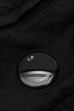 Nahaufnahme des labeltypischen Linsen-Details der C.P. Company Gürteltasche schwarz aus wasserabweisender Microfaser mit Crinkle-Optik.