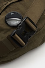 Nahaufnahme der olivfarbenen C.P. Company Gürteltasche mit wasserabweisender Microfaser, Crinkle-Optik, Label-Linse und robustem Gurtverschluss.