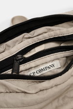 Nahaufnahme der geöffneten C.P. Company Gürteltasche grau mit wasserabweisender Microfaser, Reißverschlüssen und Innenfach, von oben fotografiert.