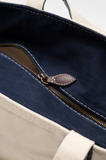 Nahaufnahme des Innenraums vom Polo Ralph Lauren Shopper creme/navy, Perspektive von oben, Canvas aus Baumwolle, Außentasche, zwei Innenfächer, Zipper, Tragegriffe, Maße ca. 57x34x19 cm.