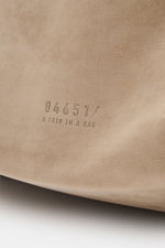Nahaufnahme des beigen Veloursleders mit 04651/-Prägung des 04651/ A trip in a bag Weekender '356 Bag' aus schräger Perspektive.