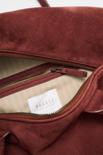 Nahaufnahme des geöffneten Weekender '356 Bag' rotbraun von 04651/ A trip in a bag, aus geschmeidigem Veloursleder mit sichtbarem Reißverschluss innen.