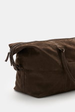 Close-up side view of the 04651/ A trip in a bag Weekender '3 Day Bag' dark brown made of soft nubuck leather with silver-colored hardware, robust carrying handles, two-way zipper, 04651/- embossing on the front, small address compartment, spacious main c