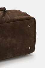 Close-up view of the bottom corner of the 04651/ A trip in a bag Weekender '3 Day Bag' dark brown, showing soft nubuck leather, silver-colored hardware, robust carrying handles, two protective metal feet, and detailed stitching; features include two-way z