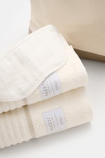 Nahaufnahme des 04651/ A trip in a bag Reise-Sets 'Voyage' creme/weiß mit Bademantel, Badetuch, Schlafmaske und Canvas-Shopper, seitliche Perspektive.