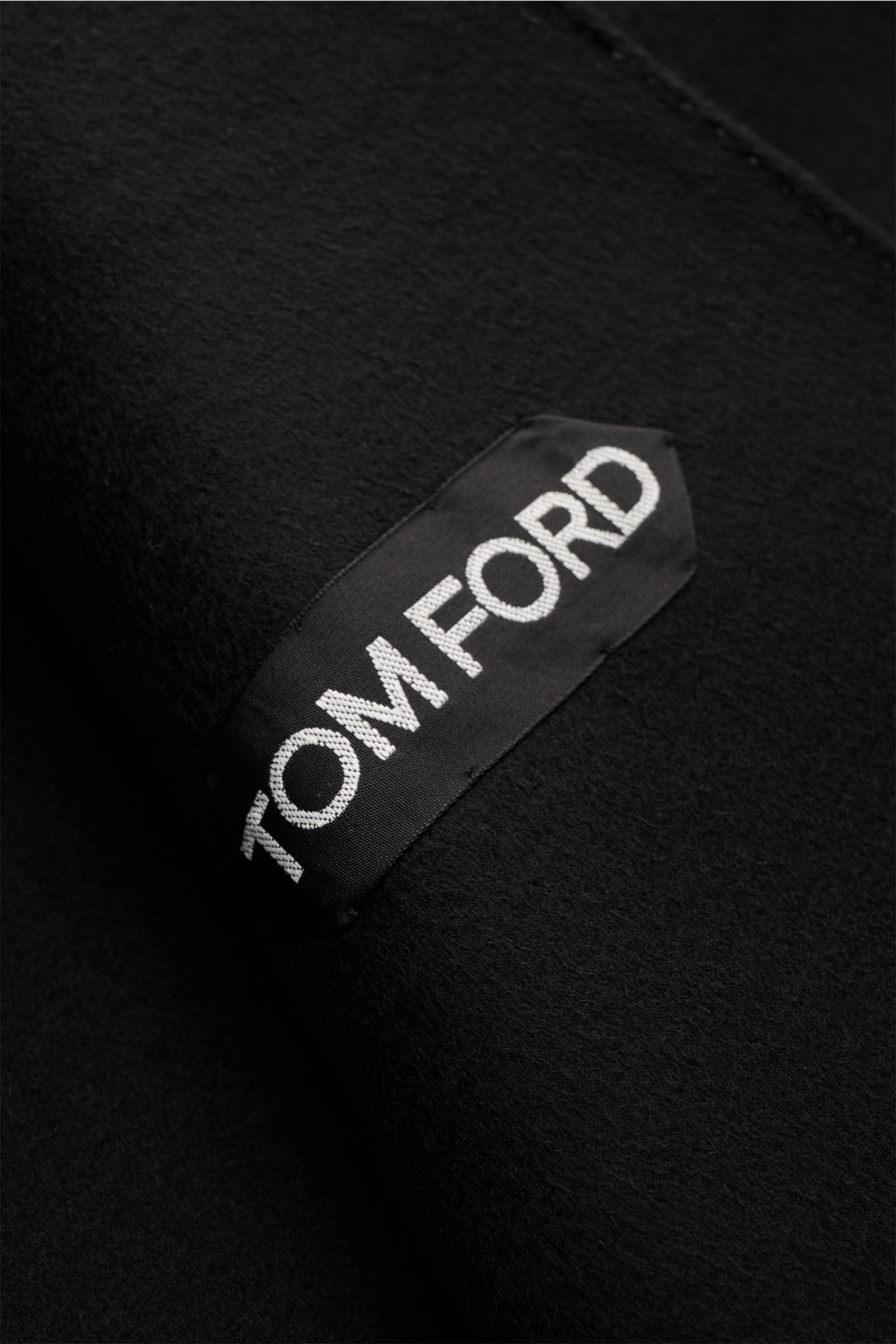 Close-up front view of the black Tom Ford Mantel schwarz label on a soft wool-cashmere blend fabric, highlighting the premium texture.

Souverän durch die kalte Jahreszeit: Dieser Mantel von TOM FORD aus edlem Woll-Mix mit Cashmere wird von der markent