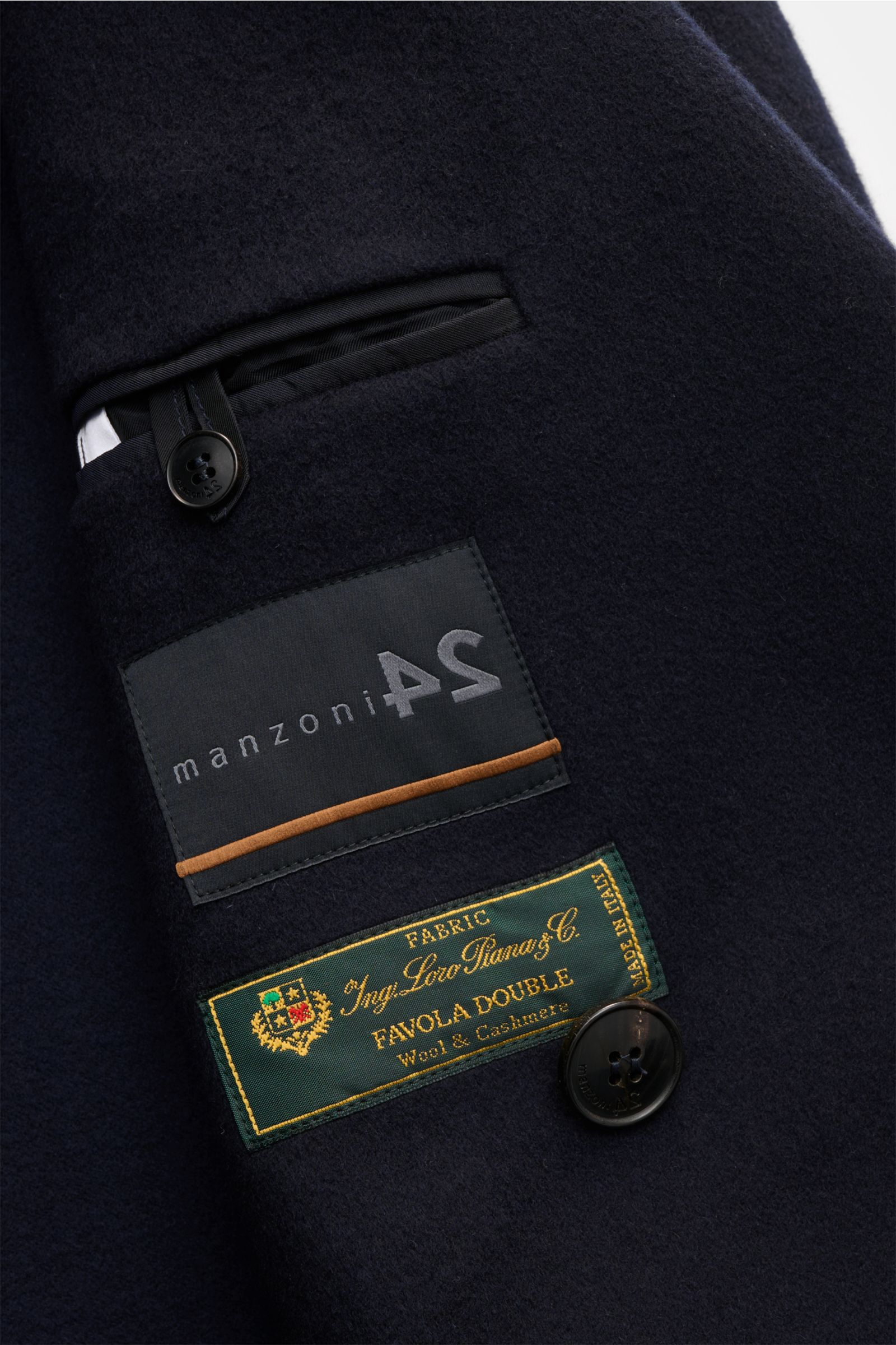 Nahaufnahme des Innenfutters eines dunkelblauen Manzoni 24 Mäntel - U640 mit Etiketten und Knopf aus Woll-Cashmere, seitliche Perspektive.
