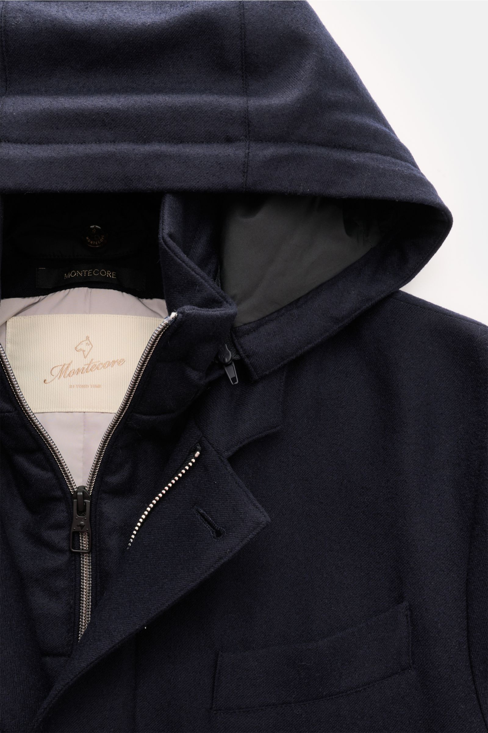 Close-up front view of the Montecore Short down coat, navy, showing the detachable hood, silver zipper, and jetted breast pocket in elastic virgin wool.

An elegant essential for winter: This down jacket by MONTECORE is warm and comfortable, with an el